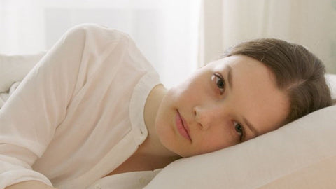 Femme allongée sur un lit, le regard songeur, évoquant une baisse de libido et l'absence de désir